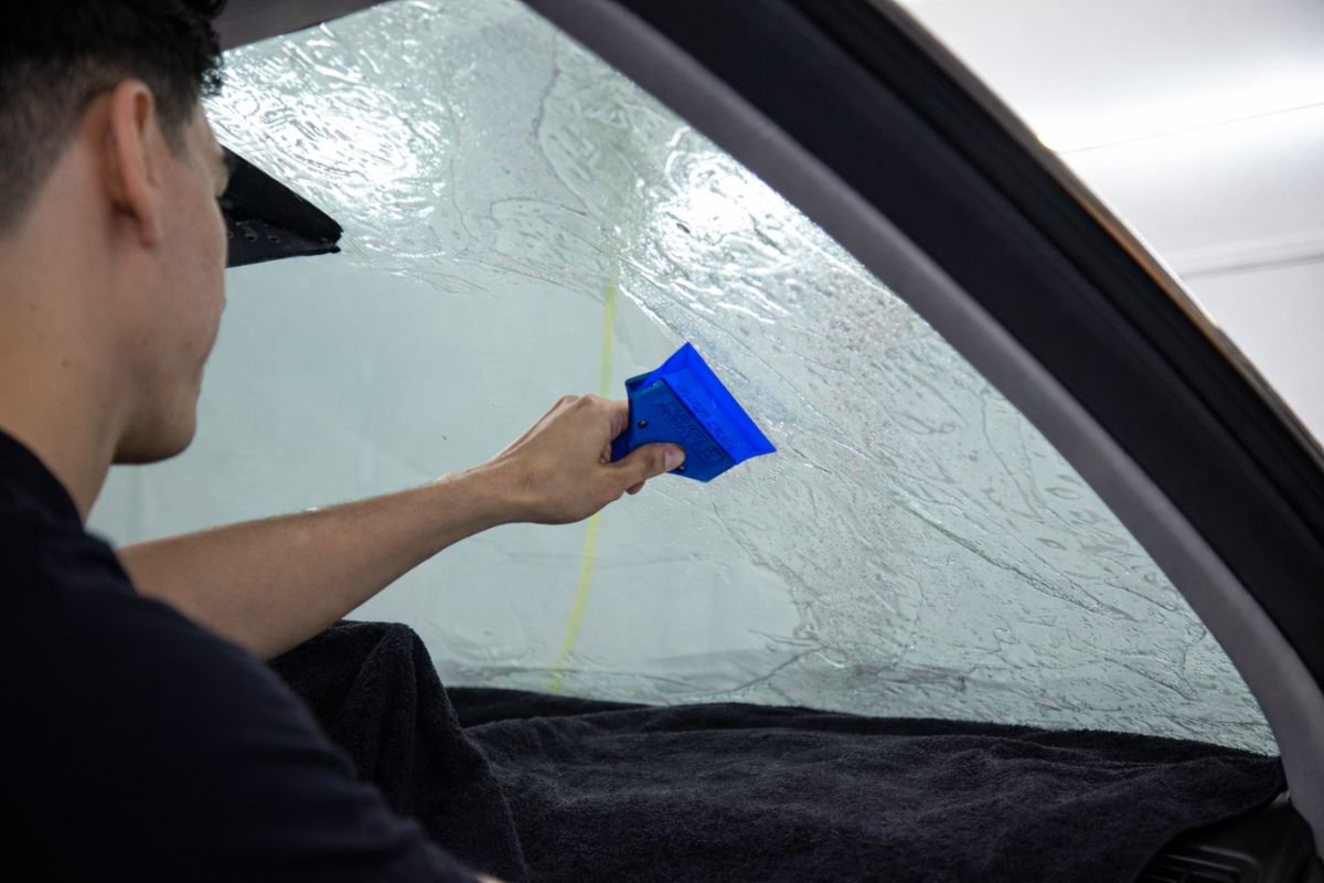 Proceso profesional de polarizado automotriz con herramientas especializadas y acabado limpio.